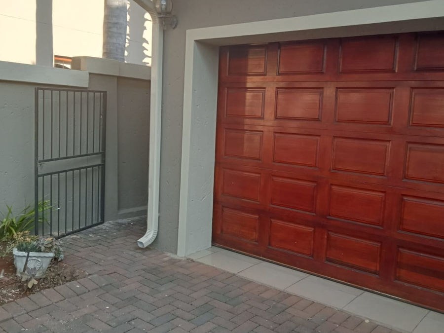 A garage door with a red-brown wood finish beside a painted wall