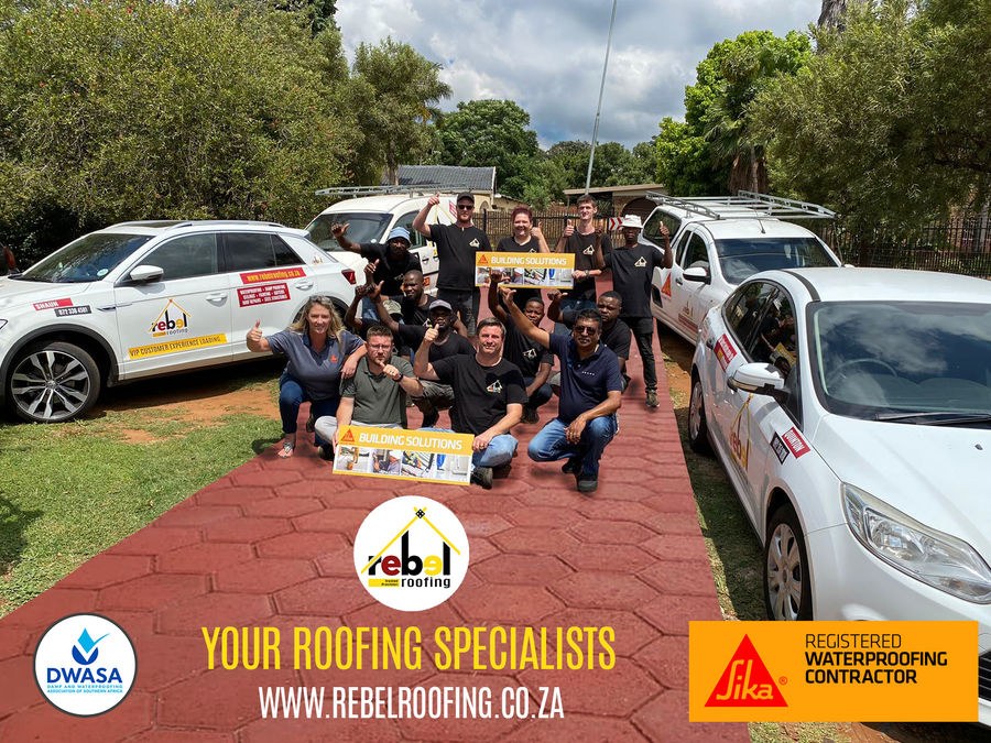 The Rebel Roofing team giving thumbs up between branded vehicles, with DWASA and Sika logos below