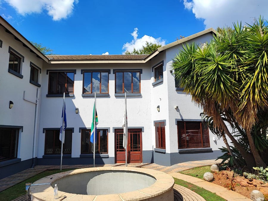 A two-storey office building painted white, with flagpoles at the entrance