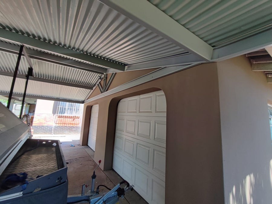 The underside of a steel carport built over two garage doors
